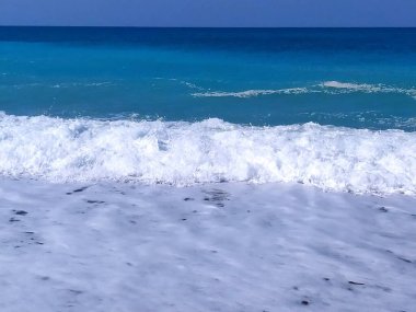 Deniz mavisi su, beyaz köpük ve dalgalar.