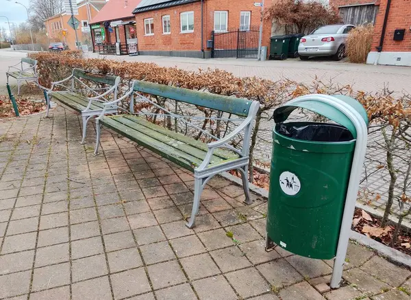Şehir ortamında yeşil çöp kutusu ve banklar
