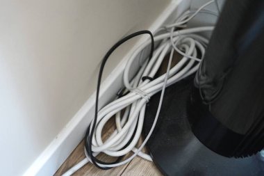 Beyaz siyah kablolar yerdeki bağlantıları düzensiz karmaşada güvenli olmayan elektrik tehlikesinde kurar. Yüksek kalite fotoğraf