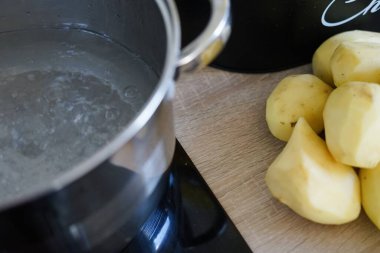 boiling water pot and peeled potato prepared for cooking puree home kitchen soup lunch dinner meal . High quality photo clipart