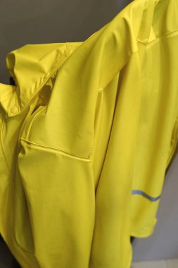 Yağmura dayanıklı sarı kapüşonlu, yağmurdan sonra ıslanan askıda asılı duran yağmurluk sonbahar soğuğunu korur. Yüksek kalite fotoğraf