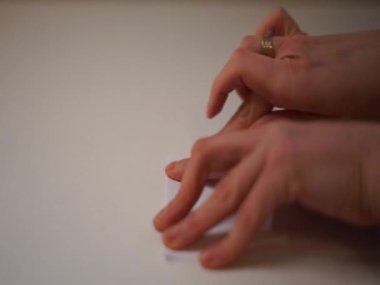 Videocu kadın ellerini katlayarak Japon figürlerindeki beyaz kağıttan origami tekne gemisi yapıyor. Yüksek kaliteli HD görüntüler