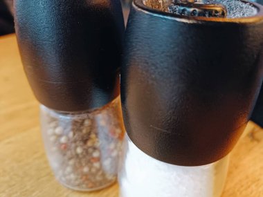 Biber taneli şeffaf tuzluk değirmeni ve fotokopi restoranı olan siyah ahşap masa. Yüksek kalite fotoğraf