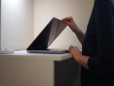 Videocu kadın bilgisayarını kapatıyor çalışma saatlerini bitiriyor iş hayatını dengede tutuyor ışığı kapatıyor. Yüksek kaliteli HD görüntüler