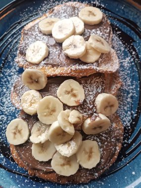 pancakes breakfast with banana chocolate cream on top blue plate restaurant cafe routine morning . High quality photo clipart