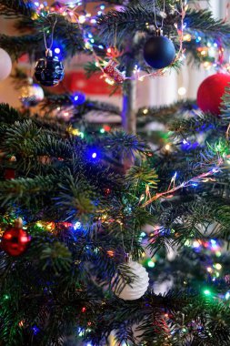 Renkli süsler ve parlak ışıklarla süslenmiş güzel dekore edilmiş bir Noel ağacı sıcak bir tatil ortamı yaratıyor..