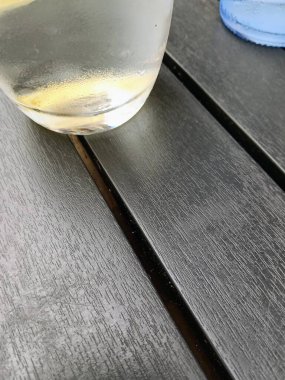 Karanlık ahşap bir masanın üzerinde duran bir bardak suyun yakın plan görüntüsü, gündelik bir ortamda sükunet ve sükunet sergiliyor..