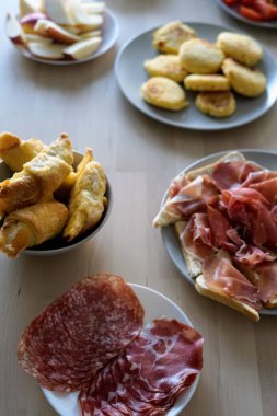 Aperatiflerin davetkar bir seçimi, pişirilmiş et ve hamur işleri dahil, ahşap bir yüzeye güzelce yerleştirilmiş, toplanma ve kutlama için mükemmel..