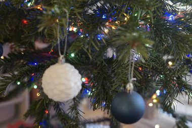 Güzel beyaz ve mavi mücevherler renkli ışıklarla çevrili bir Noel ağacında asılı, bayram havası yaratıyor..