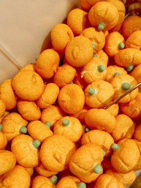 Çekici bir portakal kabağı yığını şekerleme marşmelovları üzerine yeşil serpiştirilmiş şekerler, her sonbahar gösterisi için göz alıcı bir süs oluşturur.