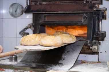 person is cooking bread in an iron oven, using firewood. high quality photo