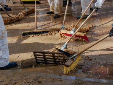 people in white suits, wellies and brushes removing mud, volunteer action, one month after the Valencia floods, in Paiporta on December 3, 2024 clipart