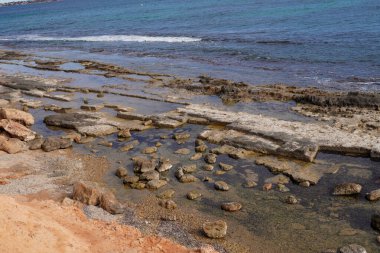 small archaeological ruins, from a Roman quarry, at the water limit of a beach, Pilar de la Horadada, can be seen very well as the water is practically calm clipart