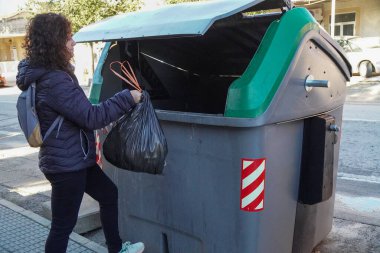 Kadının biri organik bir konteynıra çöp atıyor. Geri dönüşüm kavramı.