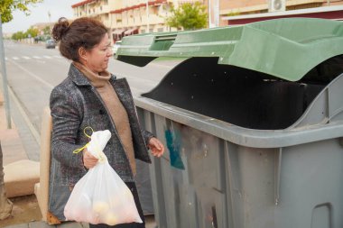 Daha sonra geri dönüşüm için konteynıra organik atık atan kişi