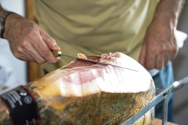 Jambon makası, elinde tuttuğu bıçakla ince dilimler kesiyor.