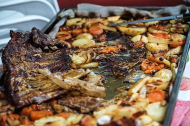 Kaburga ve patatesli rosto, lokantalar arasında paylaşılmaya hazır, domates, sarımsak ve soğanla birlikte.