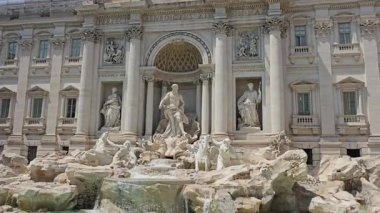 Trevi Çeşmesi 'nin ve içinde bulunduğu binanın manzarası, pırıl pırıl, temiz heykelleri ve berrak, şeffaf suyuyla, açık, çok sıcak bir yaz gününde.