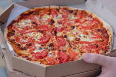 Açık havada pizza kutulu bir adam. Margarita pizza yakın çekim.