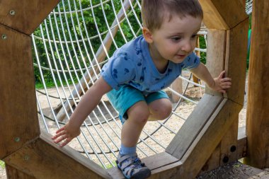 Mavi elbiseli küçük çıplak ayaklı bir çocuk modern bir ahşap oyun alanında yürüyor. Yüksek kalite fotoğraf