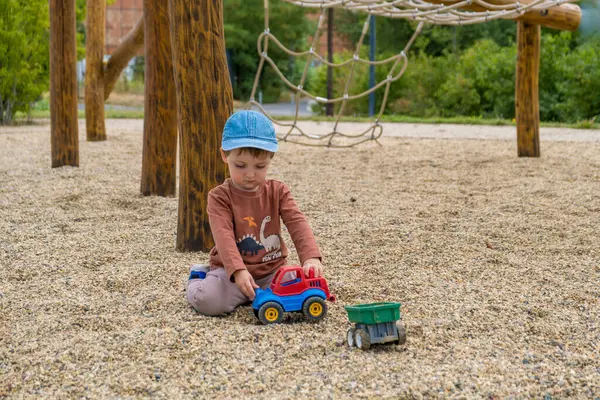 Kahverengi elbiseli küçük çıplak ayaklı bir çocuk modern bir ahşap oyun alanında yürüyor. Yüksek kalite fotoğraf