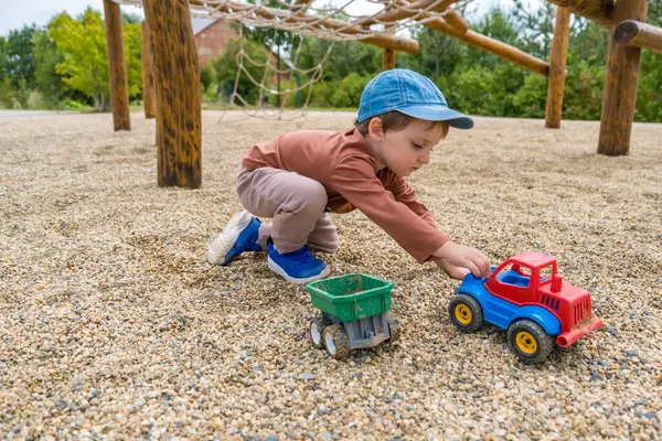 Kahverengi elbiseli küçük çıplak ayaklı bir çocuk modern bir ahşap oyun alanında yürüyor. Yüksek kalite fotoğraf