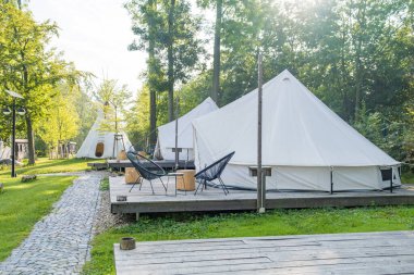 Sakin bir ormandaki çadırlar, tahta güverteler ve açık hava oturma yerleri. Yüksek kalite fotoğraf