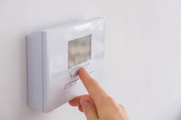 Duvardaki dijital termostatı oda sıcaklığını kontrol etmek için ayarlıyorum. Yüksek kalite fotoğraf