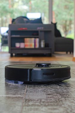 Robotik elektrikli süpürge oturma odasındaki tozları temizlerken arka planda köpek ve kanepe vardı. Yüksek kalite fotoğraf