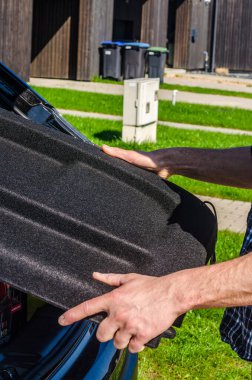 Bagajı açık, bagaj perdesi de açık. Arabanın arka perdesi insan tarafından çekiliyor. kalite fotoğraf