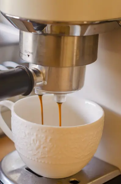 Kahve makinesinden beyaz Çin bardağına dökülen espresso yakın plan. Yüksek kalite fotoğraf