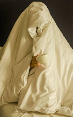  Tamamen bir battaniyeye sarılmış, bir hayalete benzeyen, elinde kupa tutan biri. Yüksek kalite fotoğraf