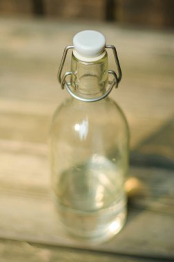 Ahşap bir yüzey üzerinde metal salıncak kapağı olan temiz bir cam şişenin yakın çekimi. Yüksek kalite fotoğraf