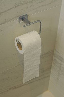 Gri bir duvarda asılı parlak bir tutacağa tuvalet kağıdı rulosu. Yüksek kalite fotoğraf