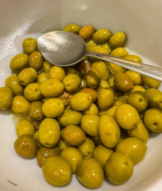 Kaşık ile beyaz kasede yeşil zeytin. Yüksek kalite fotoğraf