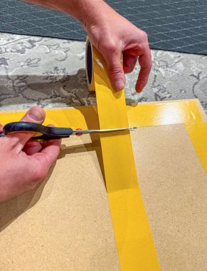 Tahta bir tahta üzerinde DIY projesi için sarı yapışkan bandı makasla kesmek. Yüksek kalite fotoğraf