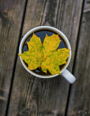 Güz Akçaağaç Yaprağı Beyaz Kupa 'da kahve ve Tahta Masa' da kahve üzerinde yüzüyor. Yüksek kalite fotoğraf