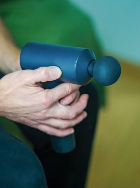 Man Using Percussion Massage Gun for Shoulder Muscle Relief. High quality photo clipart