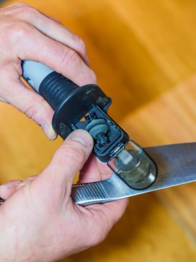 Man sharpening a knife with a handheld sharpener. High quality photo clipart