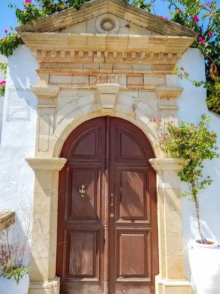 Tarihi ahşap kapı taş kemer ve Akdeniz semaları altında çiçekler çerçevelenmiş. Yüksek kalite fotoğraf