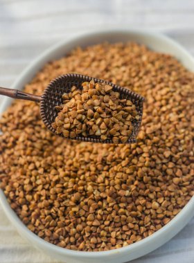 Bowl of roasted buckwheat with a vintage scoop, rustic wooden table, close-up. High quality photo clipart