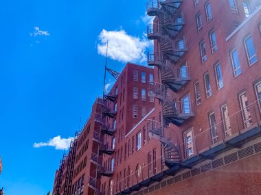 Red brick building with spiral fire escape stairs against a blue sky in Hamburg . High quality photo clipart