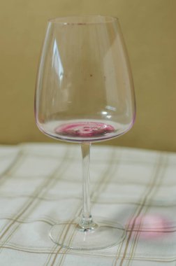 Elegant wine glass with red wine residue on a plaid tablecloth. High quality photo clipart