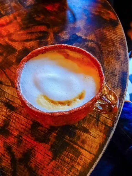 Cappuccino Anı: Yaşlı Ahşap Masaüstünde Kırsal Kil Kupasında Köpüklü Lezzet. Yüksek kalite fotoğraf
