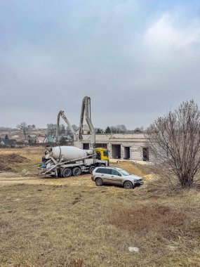 Kırsal alanda beton karıştırıcı kamyonu ve bitmemiş binası olan bir inşaat alanı. Yüksek kalite fotoğraf