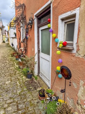 Charming alley with decorated door, colorful lights, and potted plants outside. High quality photo clipart