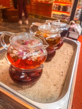 Cam çaydanlıklardaki bitki çayı tepside, kum ve canlı arka planda ortam yaratıyor. Yüksek kalite fotoğraf