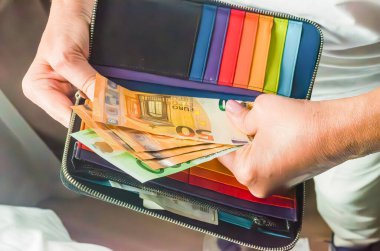 Finansal yönetimi vurgulayan nakit ve kartlarla dolu canlı bir cüzdanı ellerinde tutuyorlar. Yüksek kalite fotoğraf