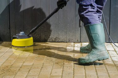 Islak fayanslarda açık hava temizliği için yüksek basınçlı temizleyici kullanıyor. Yüksek kalite fotoğraf