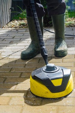 Bahar güneşinde basınçlı çamaşır makinesi ve lastik botlarla teras temizleme. Yüksek kalite fotoğraf